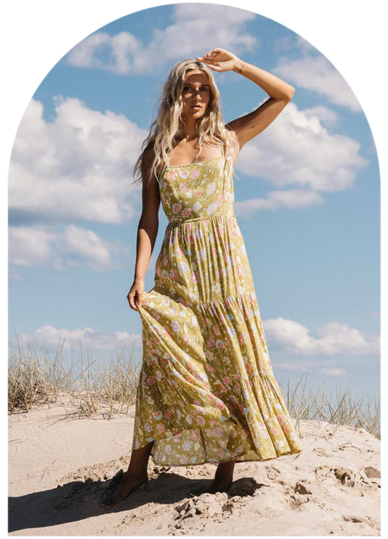 Woman standing on the beach in a green floral maxi sundress from the brand Billabong.