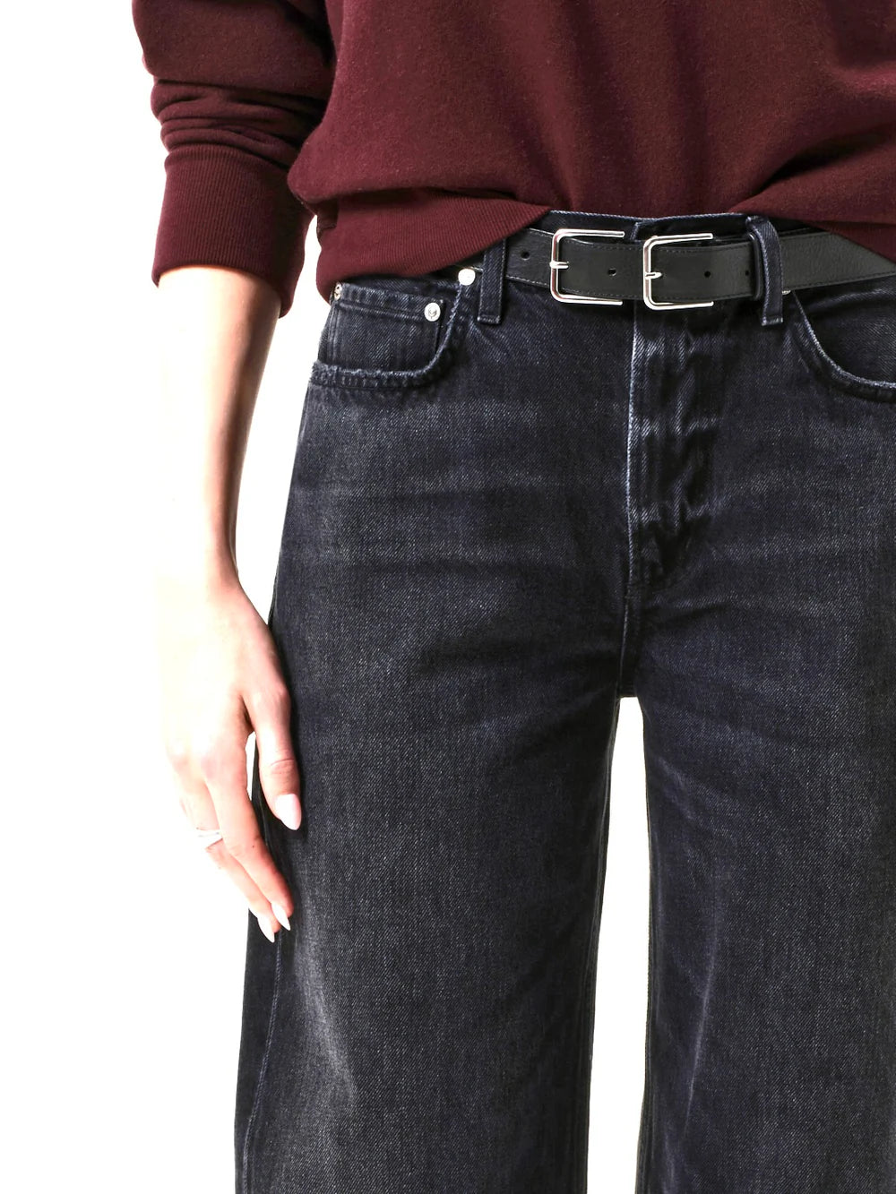 Person wearing dark jeans from Citizens Of Humanity and a burgundy top with a black belt.