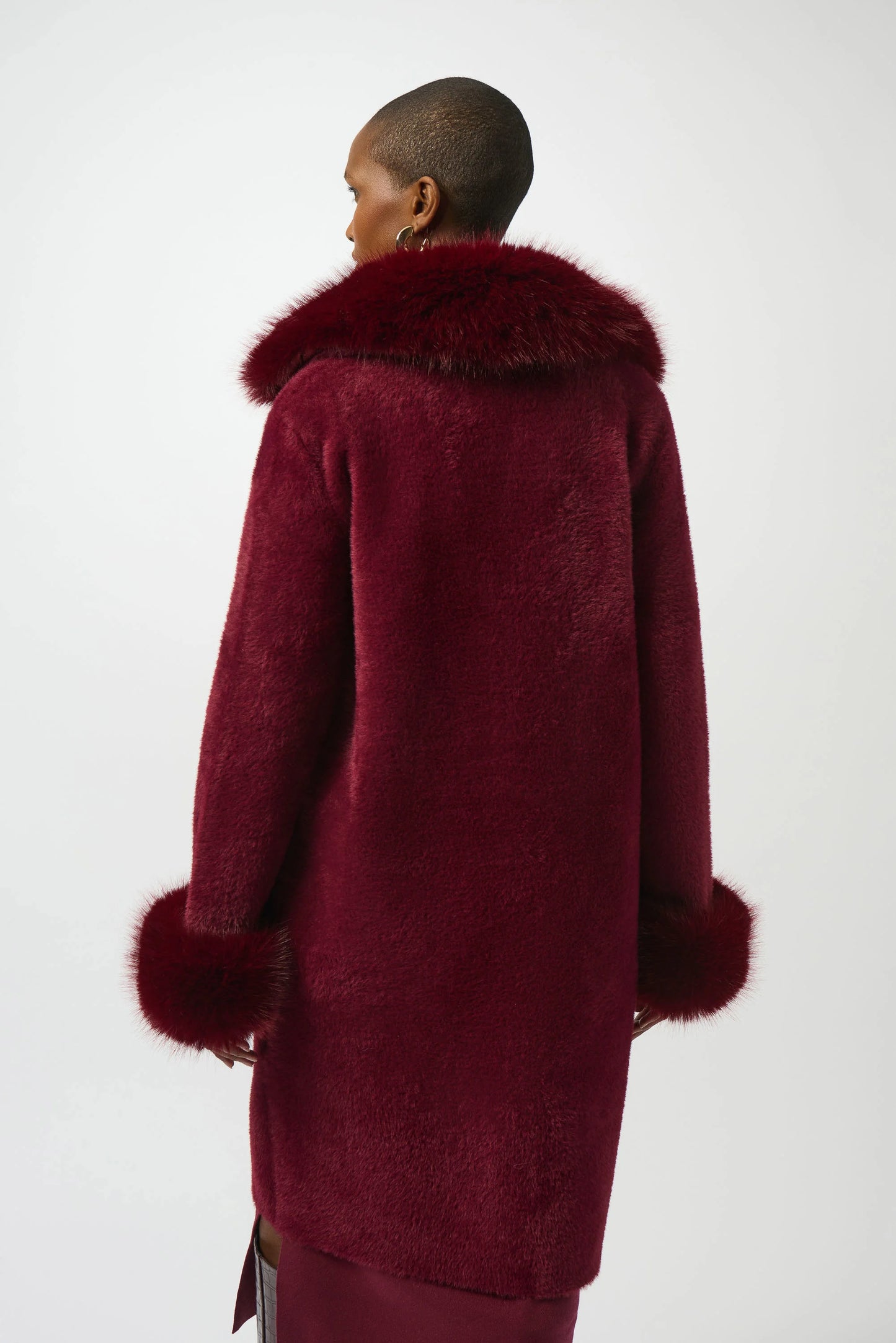 Woman wearing a red coat with fur trim from Joseph Ribkoff