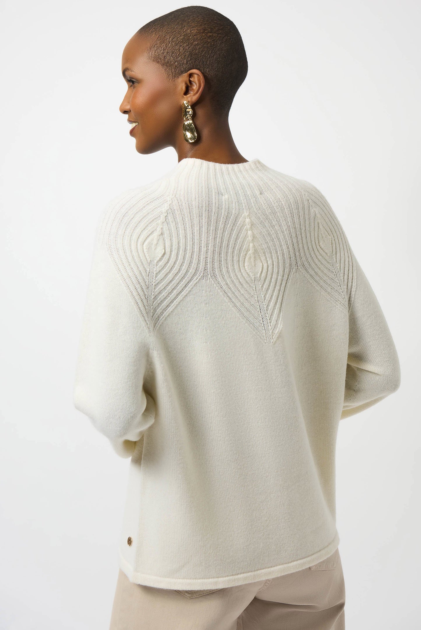 Woman wearing a cream-colored sweater with a textured pattern on a white background