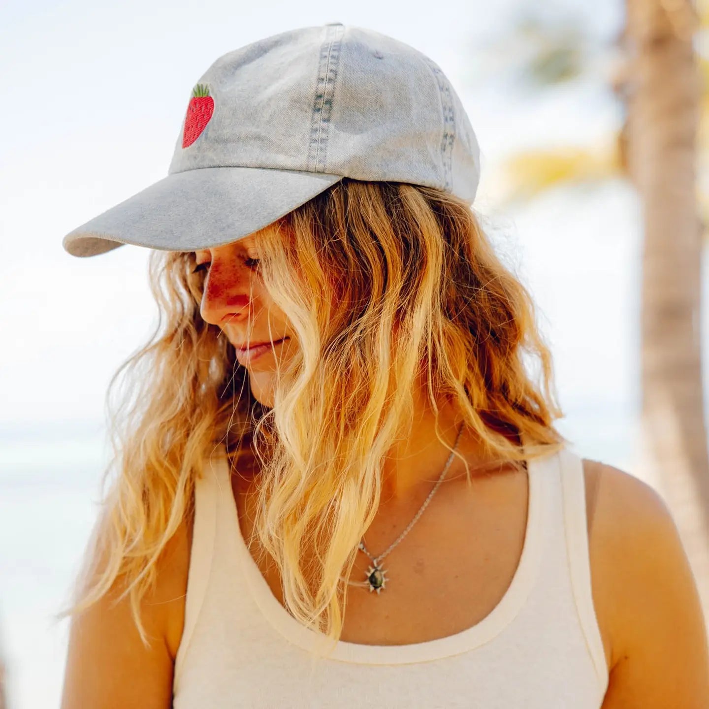 Woman wearing a light denim hat with a strawberry design on the front