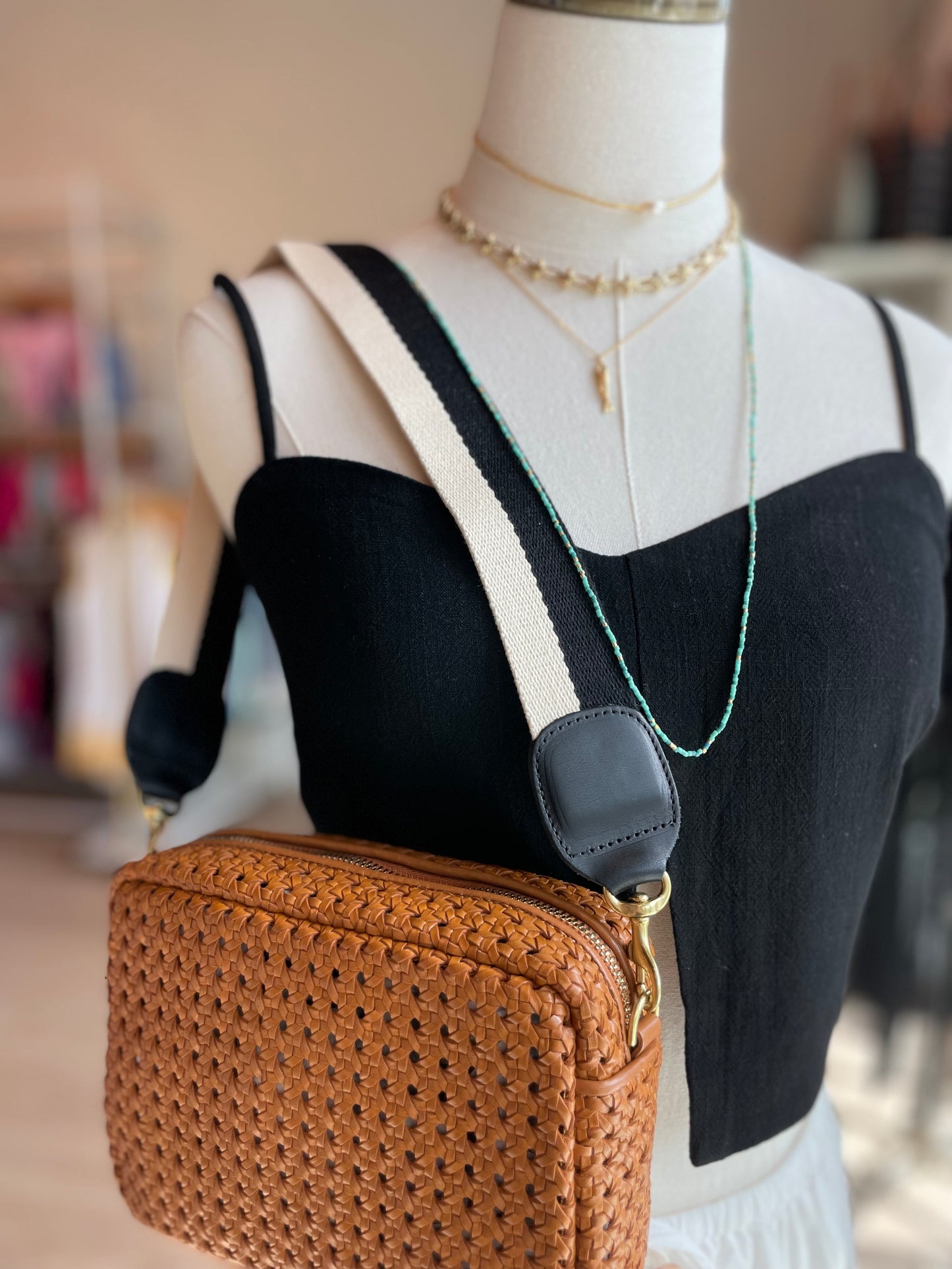 The black and white Adjustable Webbing Strap by Clare V. being worn as a shoulder strap