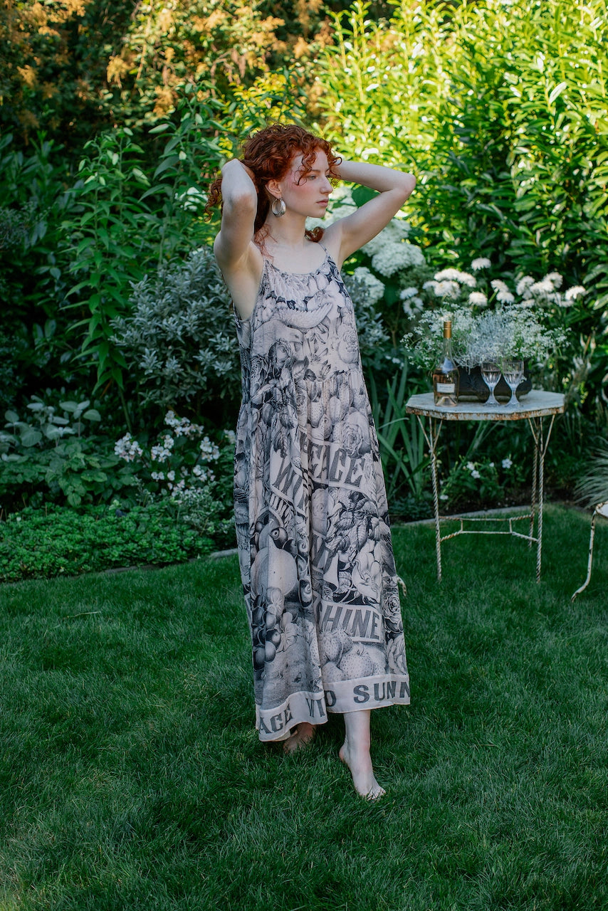 Woman in a patterned dress standing in a garden with a table and flowers in the background