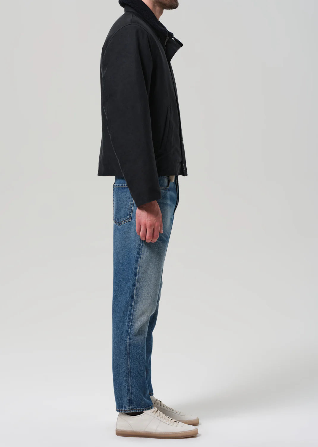 Person wearing a black jacket and blue jeans from Citizens of Humanity