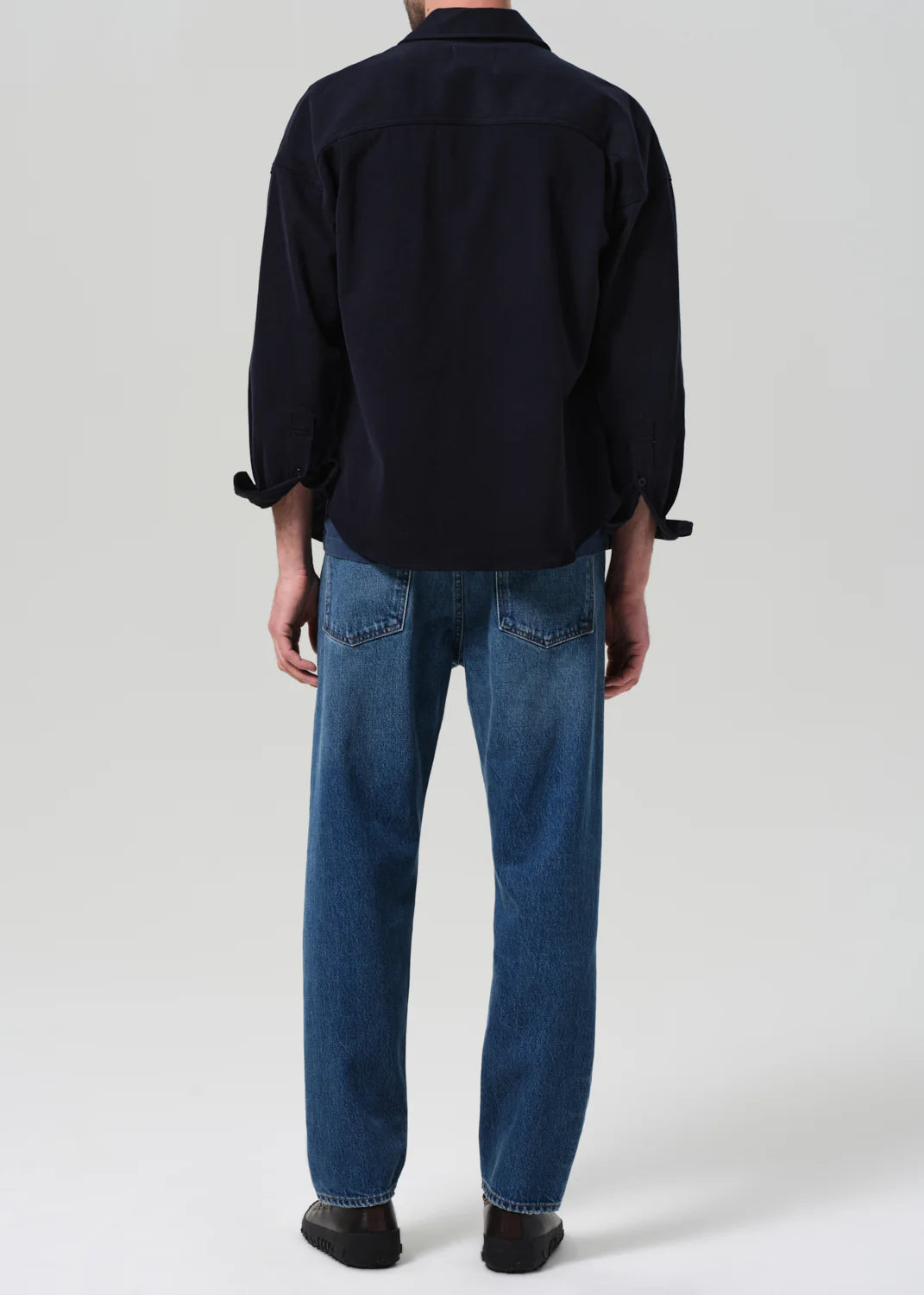Person wearing a black shirt and blue jeans with a relaxed, tapered fit