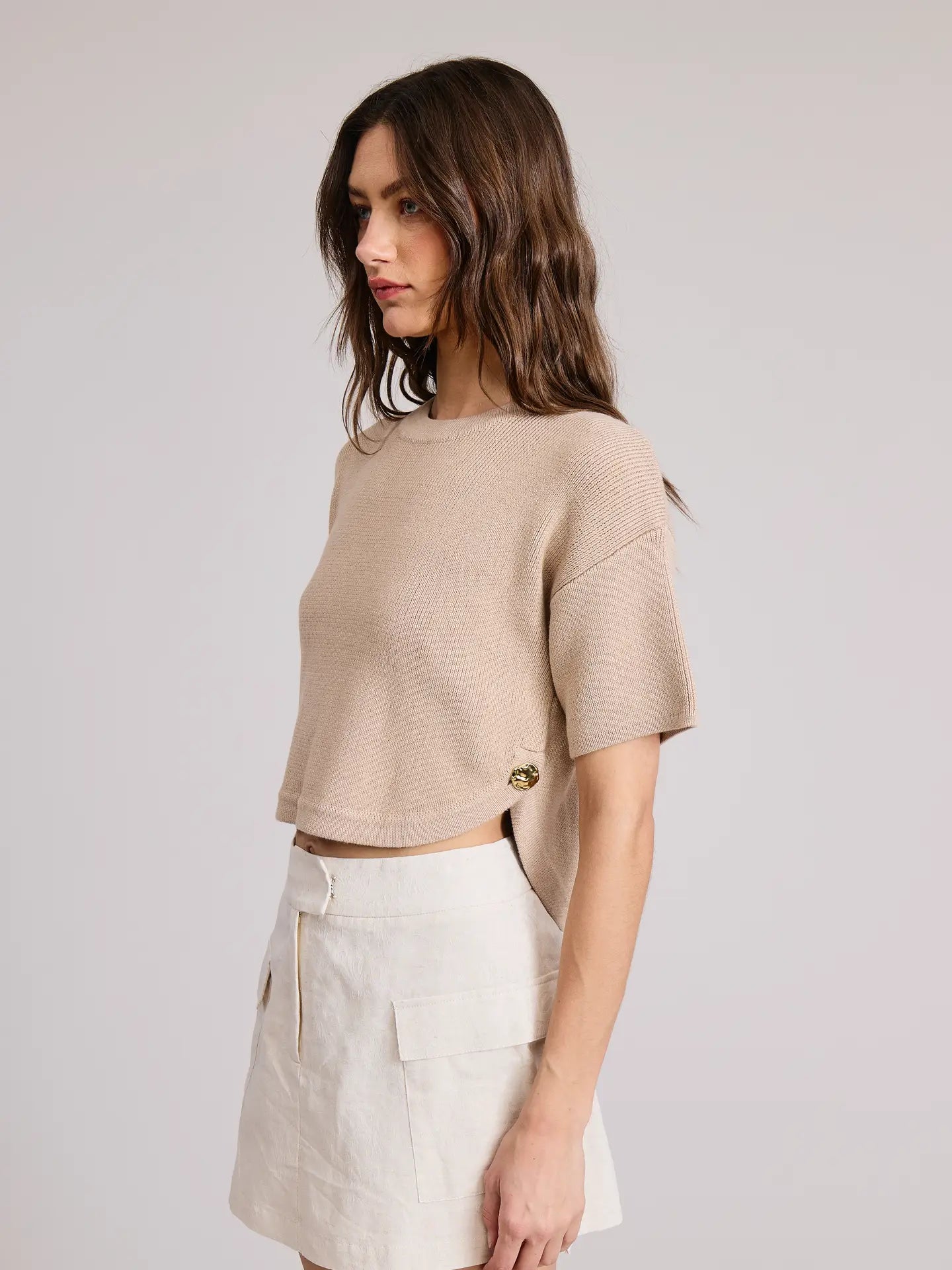 Woman wearing a beige cropped sweater with button detail by Flat White