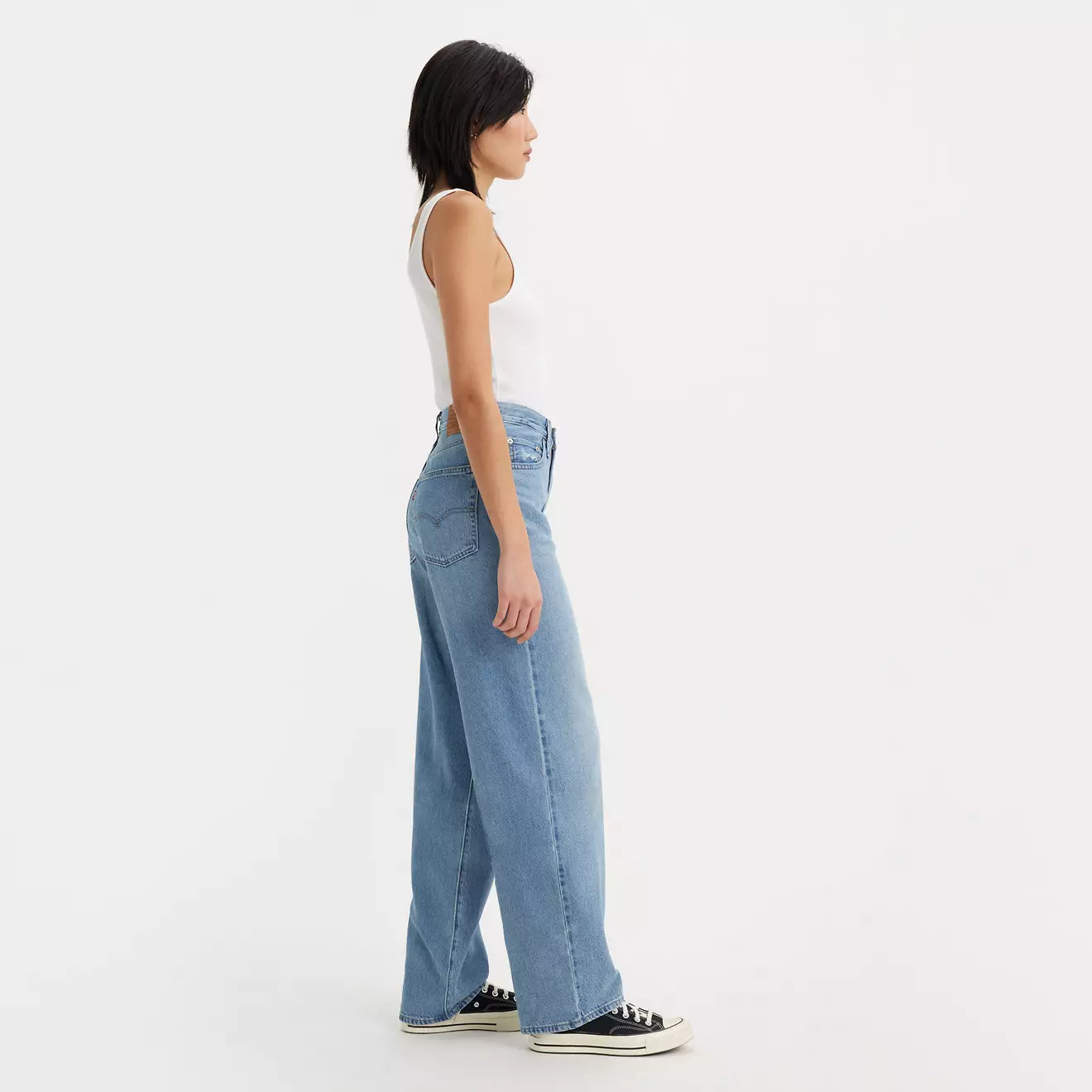 Side view of a woman wearing the In The Middle Medium Wash Distressed Baggy Dad Women's Jeans by Levi's