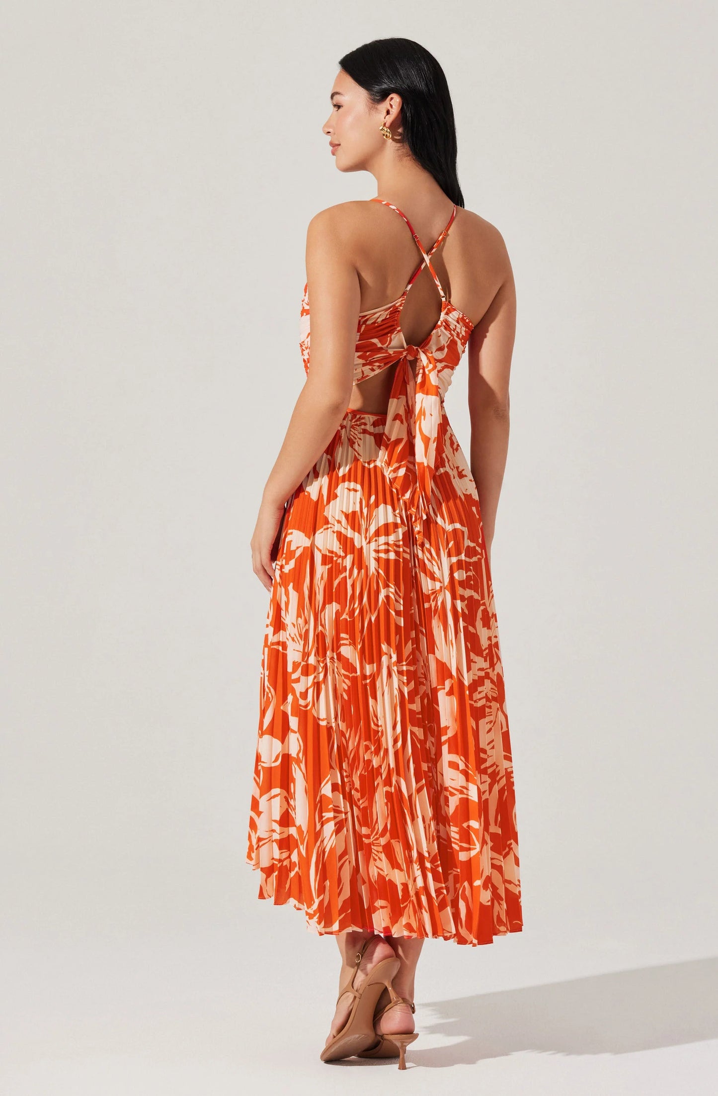 Woman wearing an orange and white patterned dress on a white background