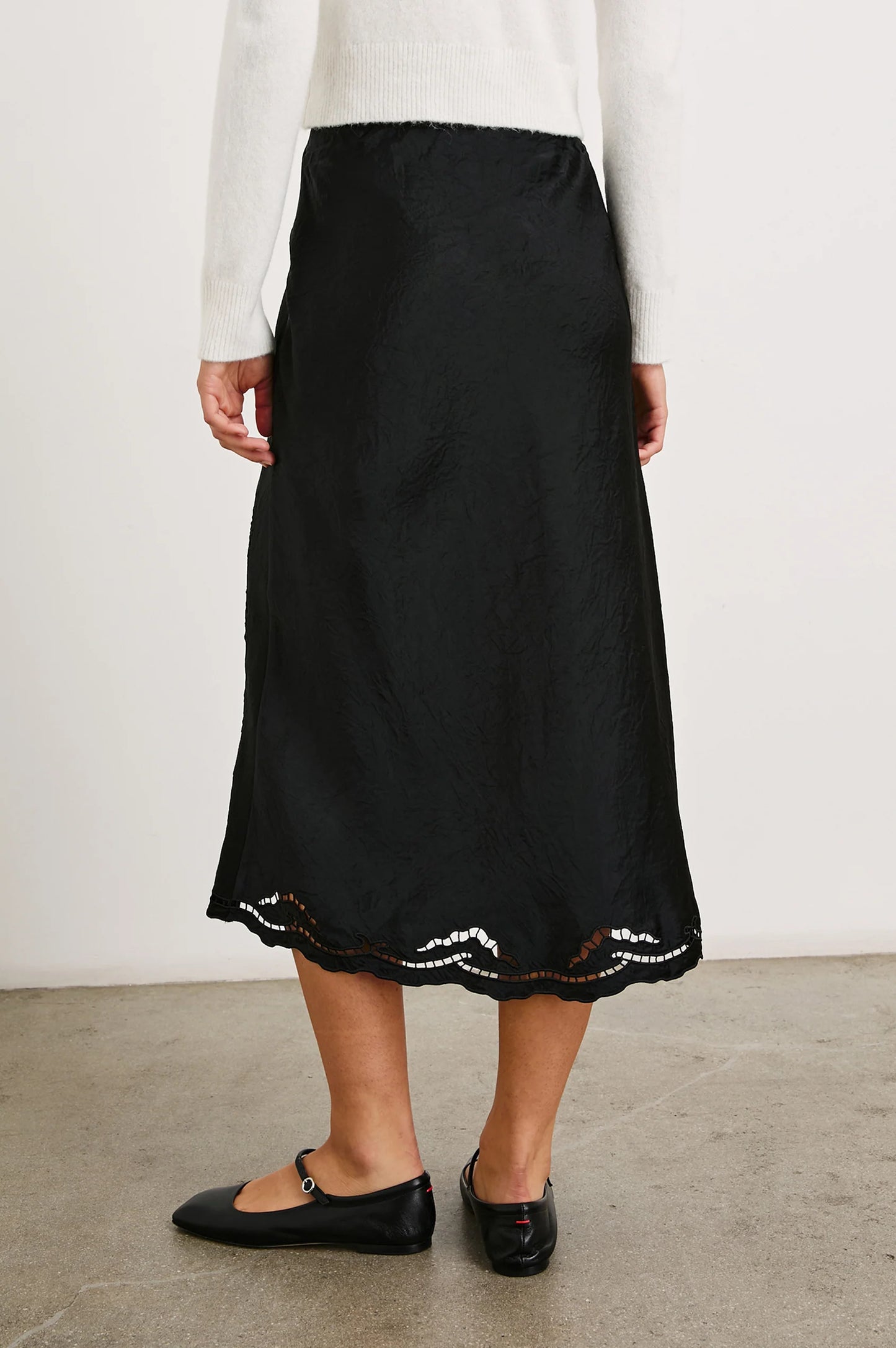 Back view of a woman wearing the Black Eyelet Anya Skirt by the brand Rails.