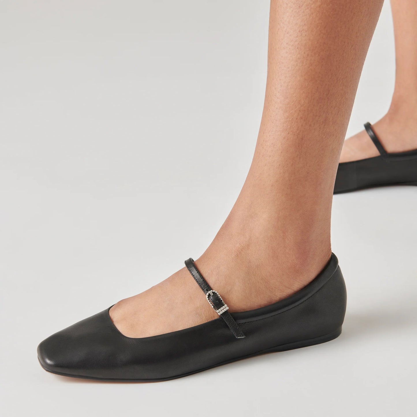 A person wearing the Black Leather Reyes Ballet Flats by the brand Dolce Vita
