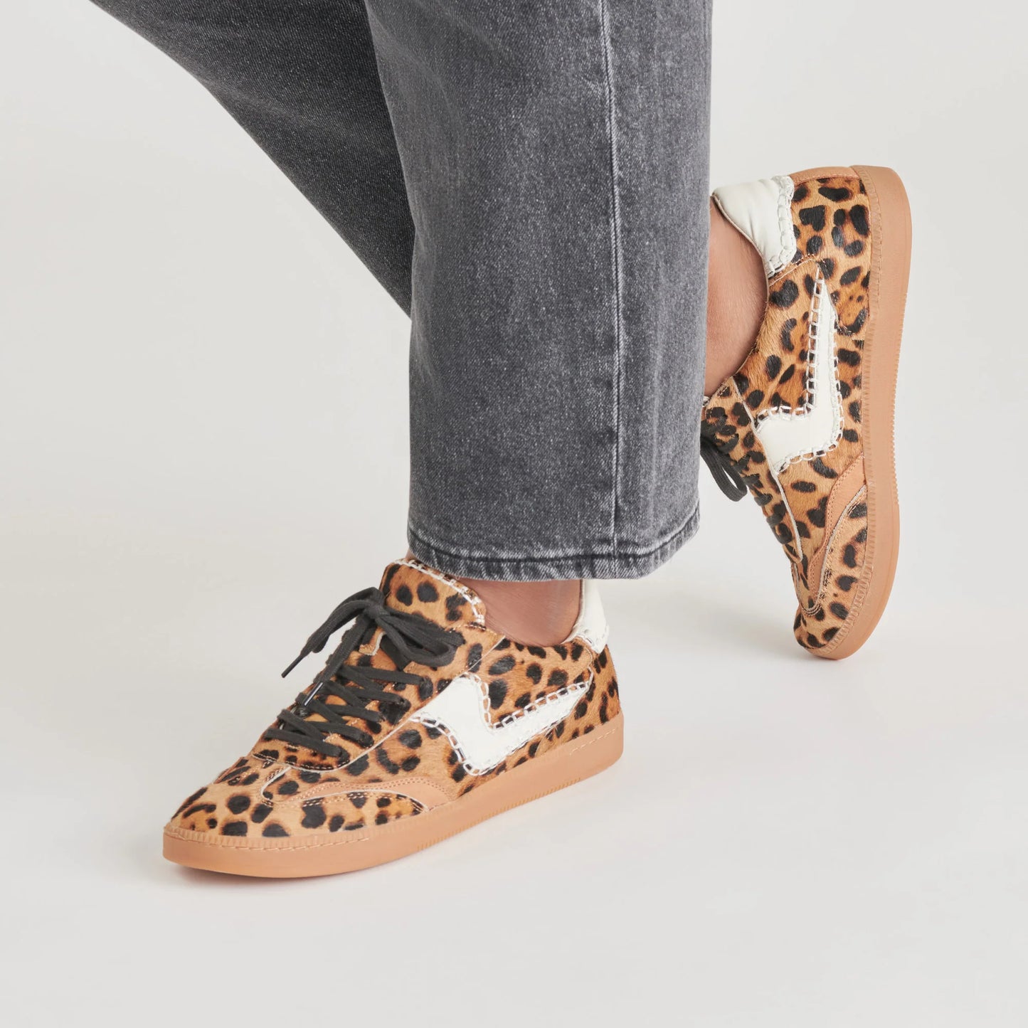 A person wearing the Notice Stitch Sneakers in Dark Leopard Calf Hair by the brand Dolce Vita
