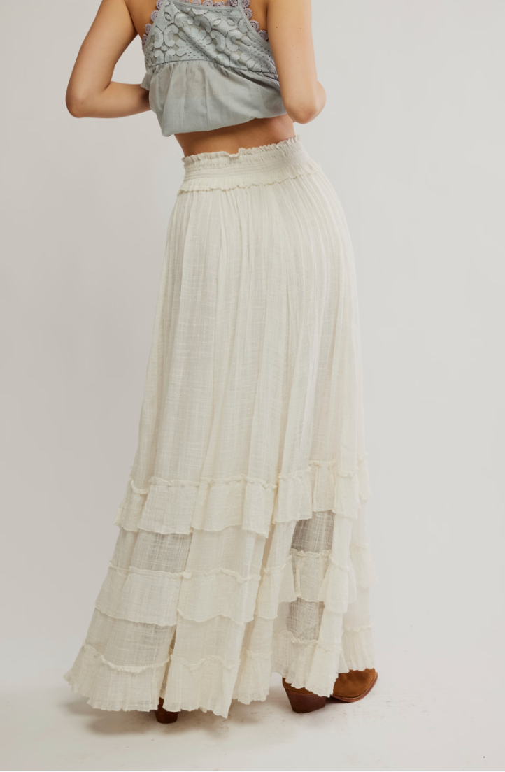 Woman wearing a long, layered white skirt on a plain background