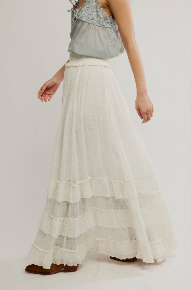 Woman wearing a light gray top and white pleated skirt from Free People