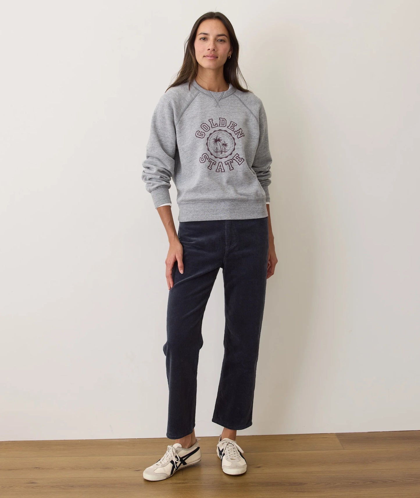 A woman wearing the Marine Layer Charlie Corduroy Straight Pant in the color Navy, paired with a crewneck sweatshirt