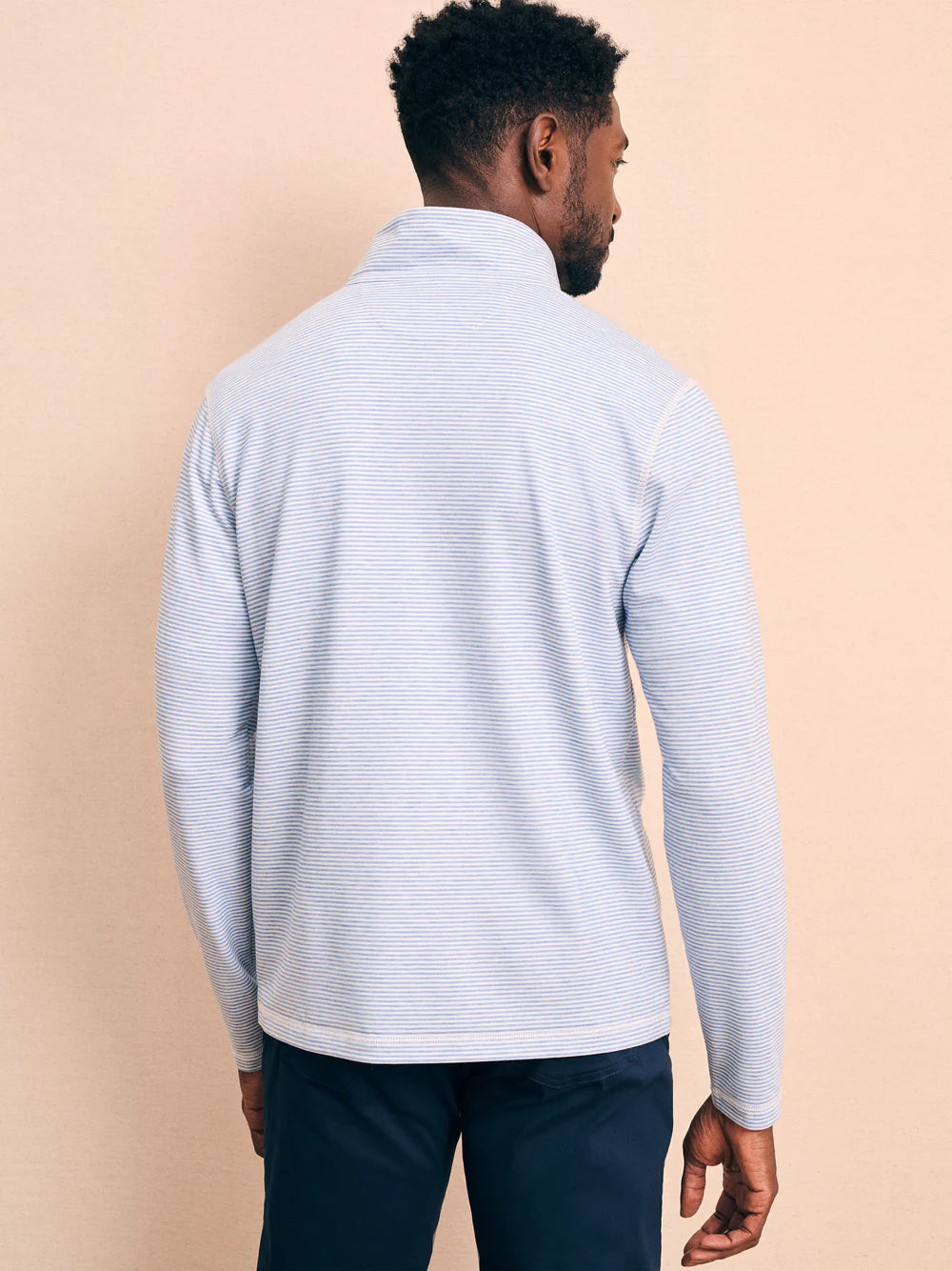 Back view of man wearing a striped quarter zip pullover by Faherty