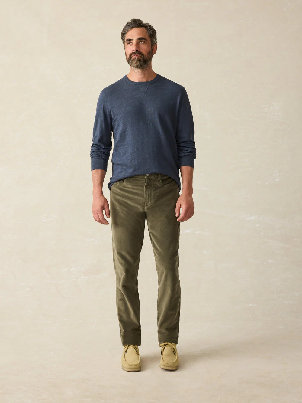 A man wearing the Stretch Terry Corduroy 5-Pocket Pant in the color Olive Surplus by Faherty