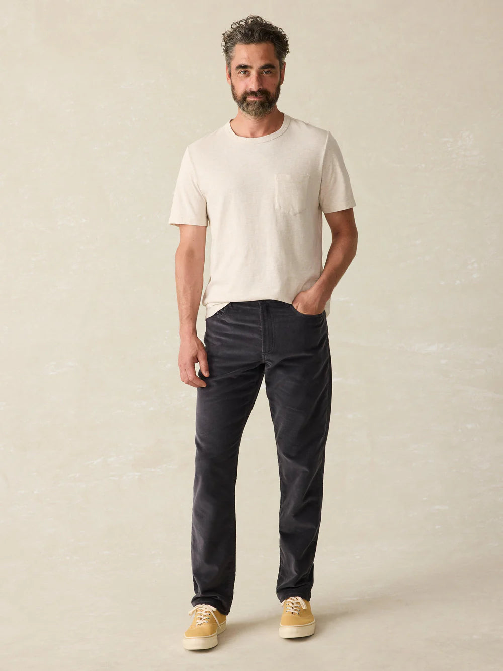 A man wearing the Stretch Terry Corduroy 5-Pocket Pant in the color Washed Charcoal, by Faherty