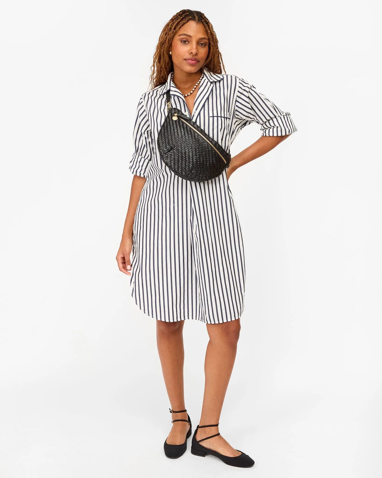 Woman wearing a black and white striped dress with a black crossbody bag from Clare V.