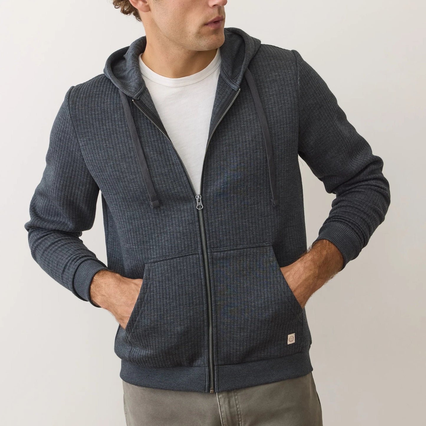 A man wearing the Black Heather Corbet Quilted Zip Hoodie by Marine Layer