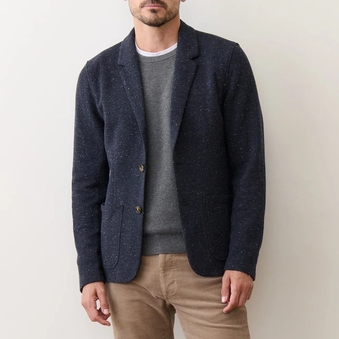 A man wearing the Dark Herringbone Pacifica Stretch Twill Blazer by Marine Layer