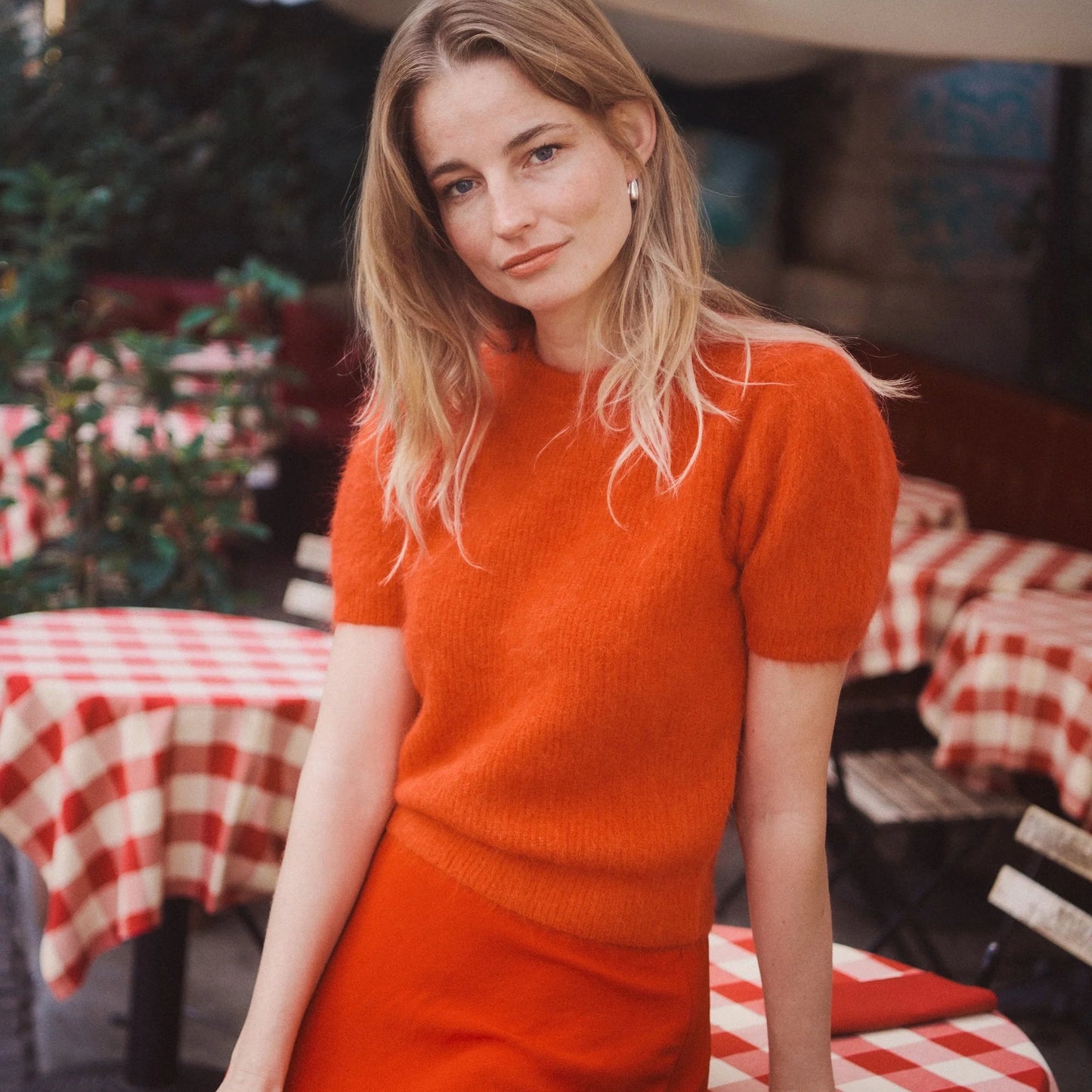 Woman in the Marine Layer Suri Alpaca Puff Sleeve Sweater sitting at a table with red and white checkered tablecloth
