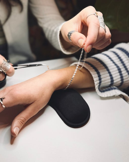 Permanent Jewelry technician sizing a Sterling Silver Aspen Chain on a customer's wrist during a Permanent Jewelry service offered by Harbour Thread.