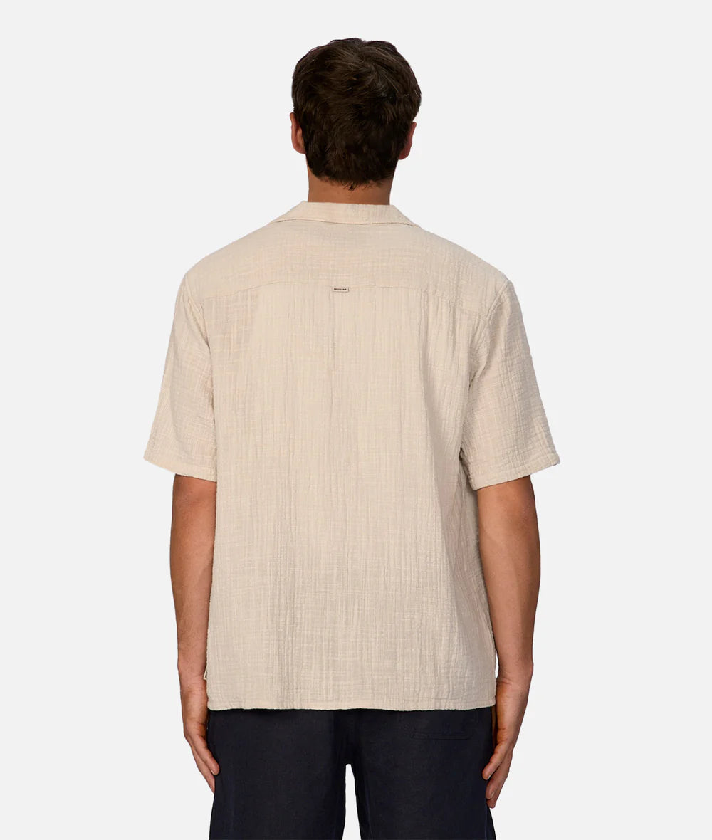 Man wearing a beige short-sleeve shirt on a white background