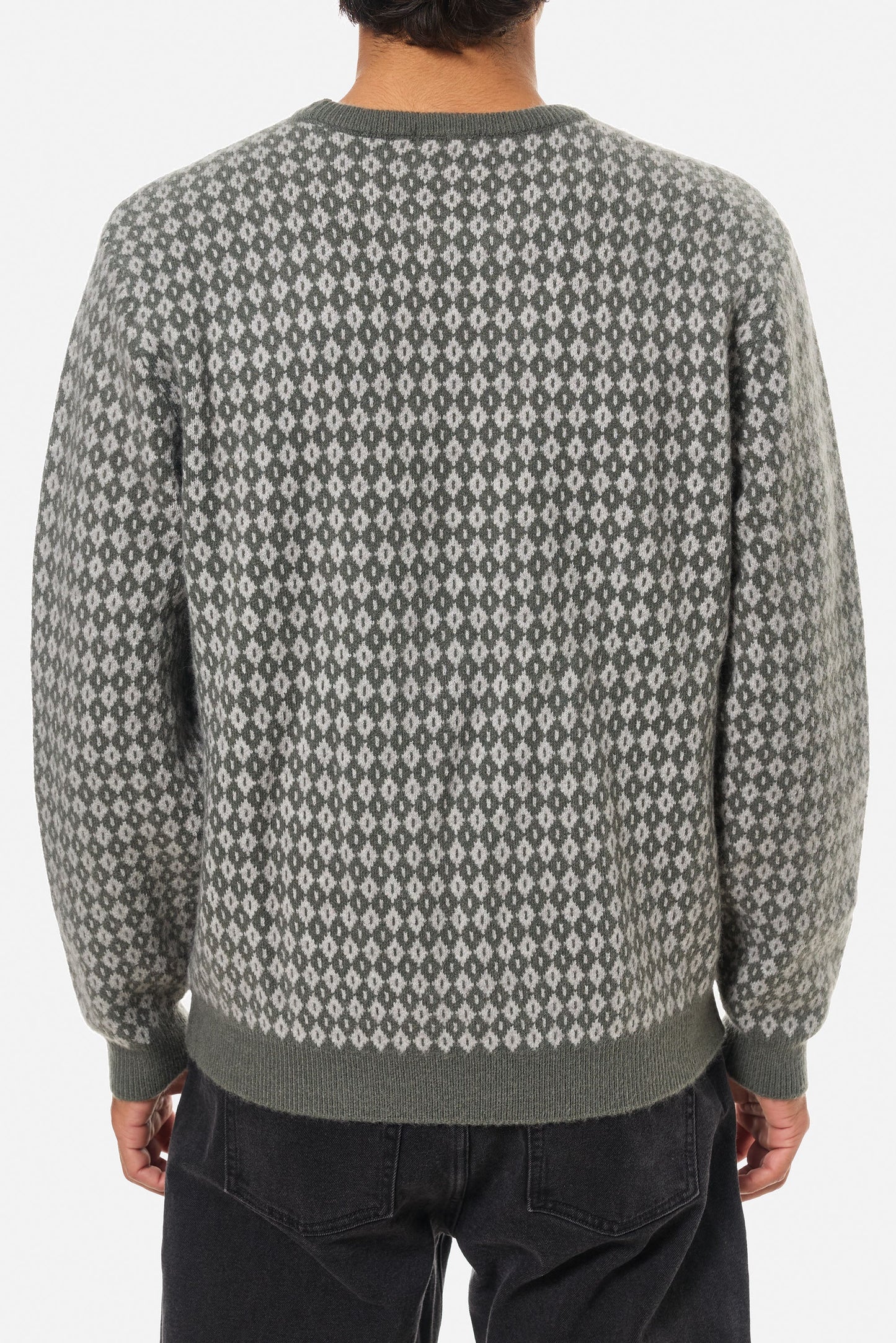 Person wearing a patterned gray sweater on a white background