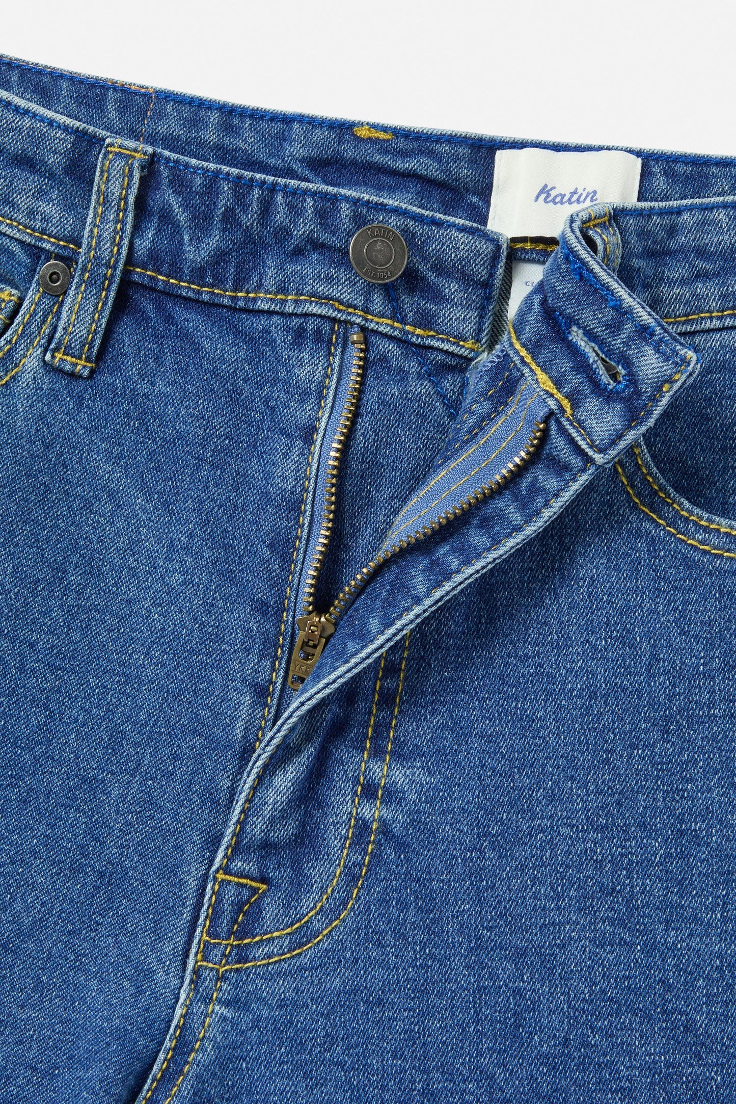 Close-up of blue denim jeans with a Katin label on a white background