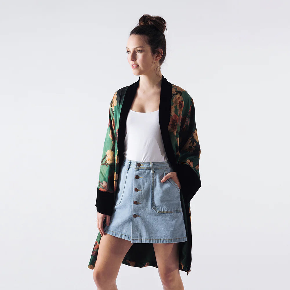 A woman wearing the Azumi Short Kimono Wrap paired with a denim mini skirt and white top
