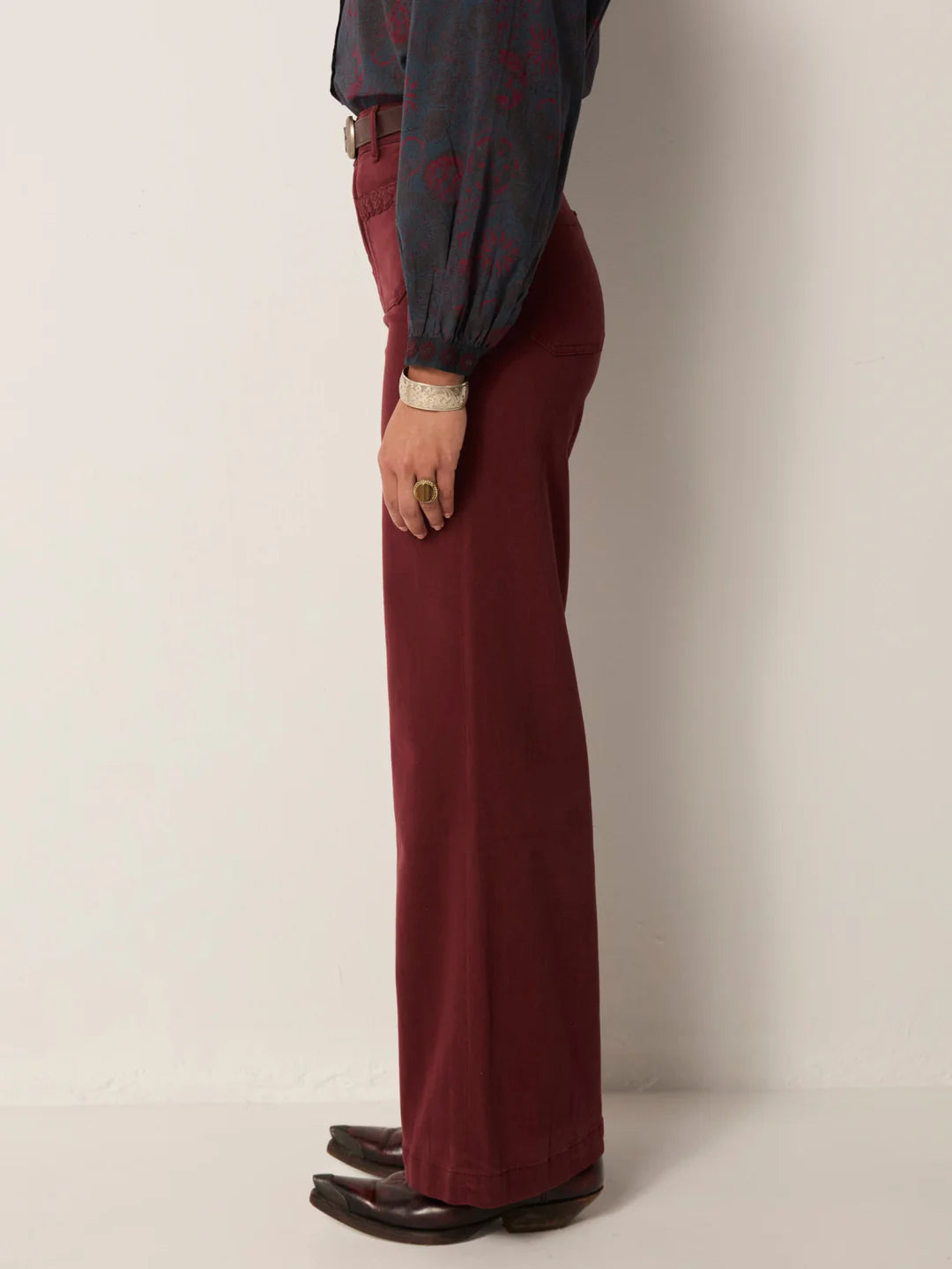 Person wearing burgundy pants and a dark shirt from Maison Hotel