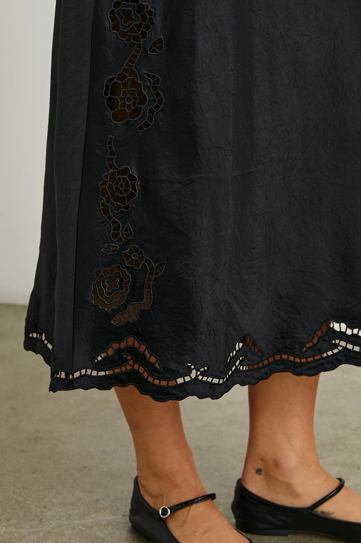 Skirt design detail on the Black Eyelet McKenna Satin Midi Dress by the brand Rails