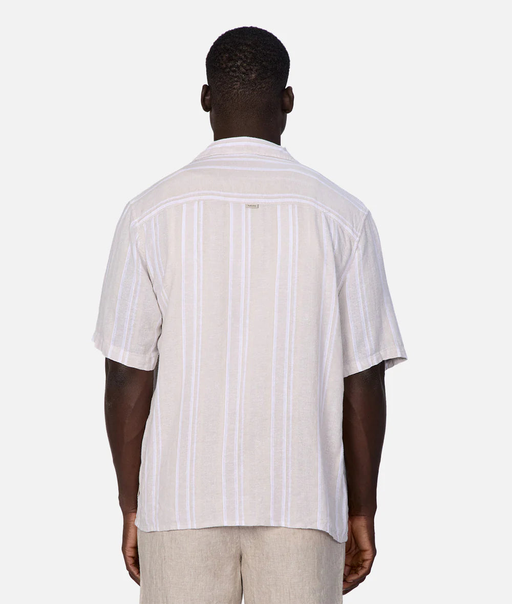 Man wearing a white short-sleeve shirt with vertical stripes on a white background