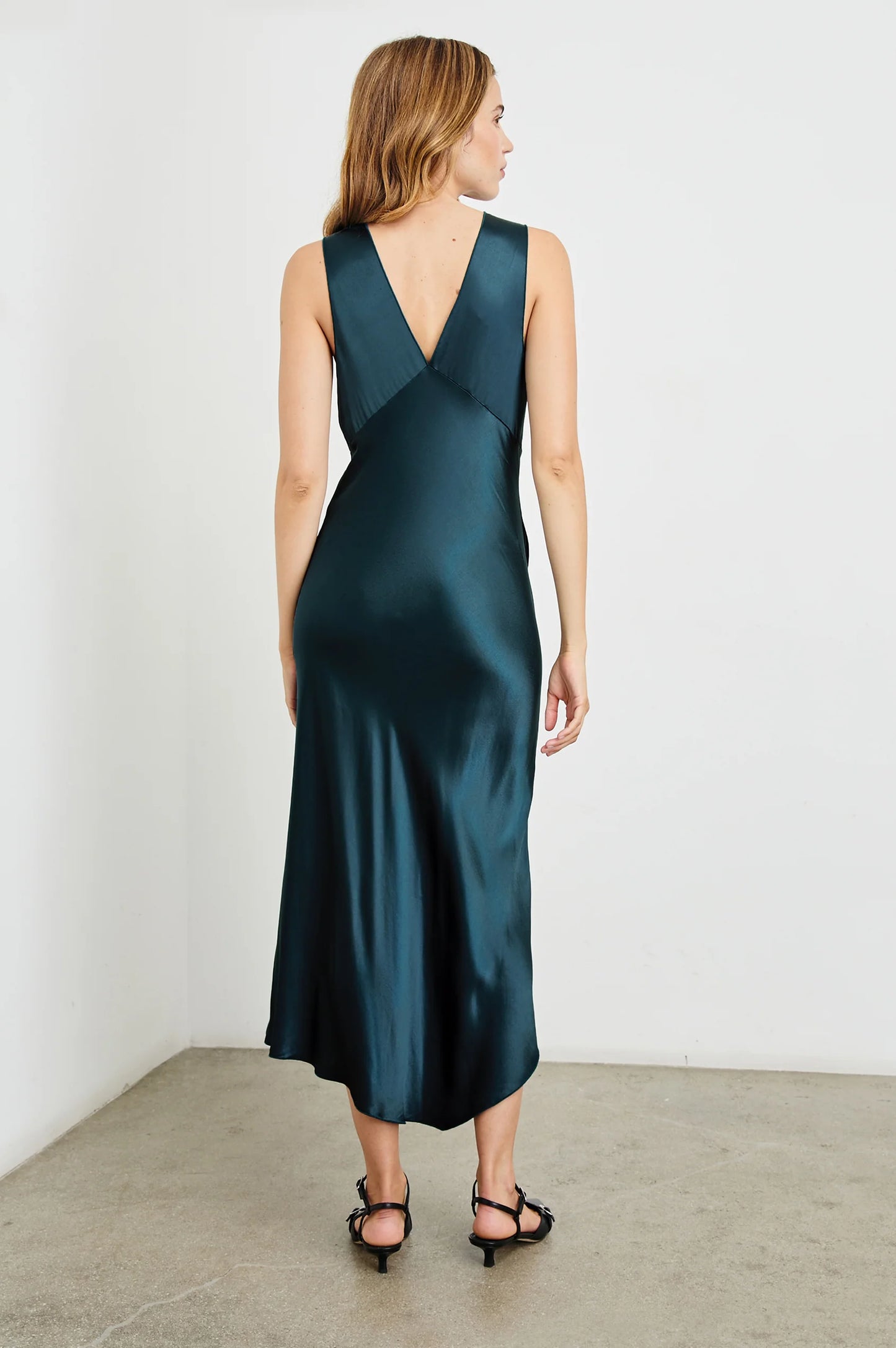 Back view of a woman wearing the Monique Midi Slip Dress in the color Deep Sea by the brand Rails