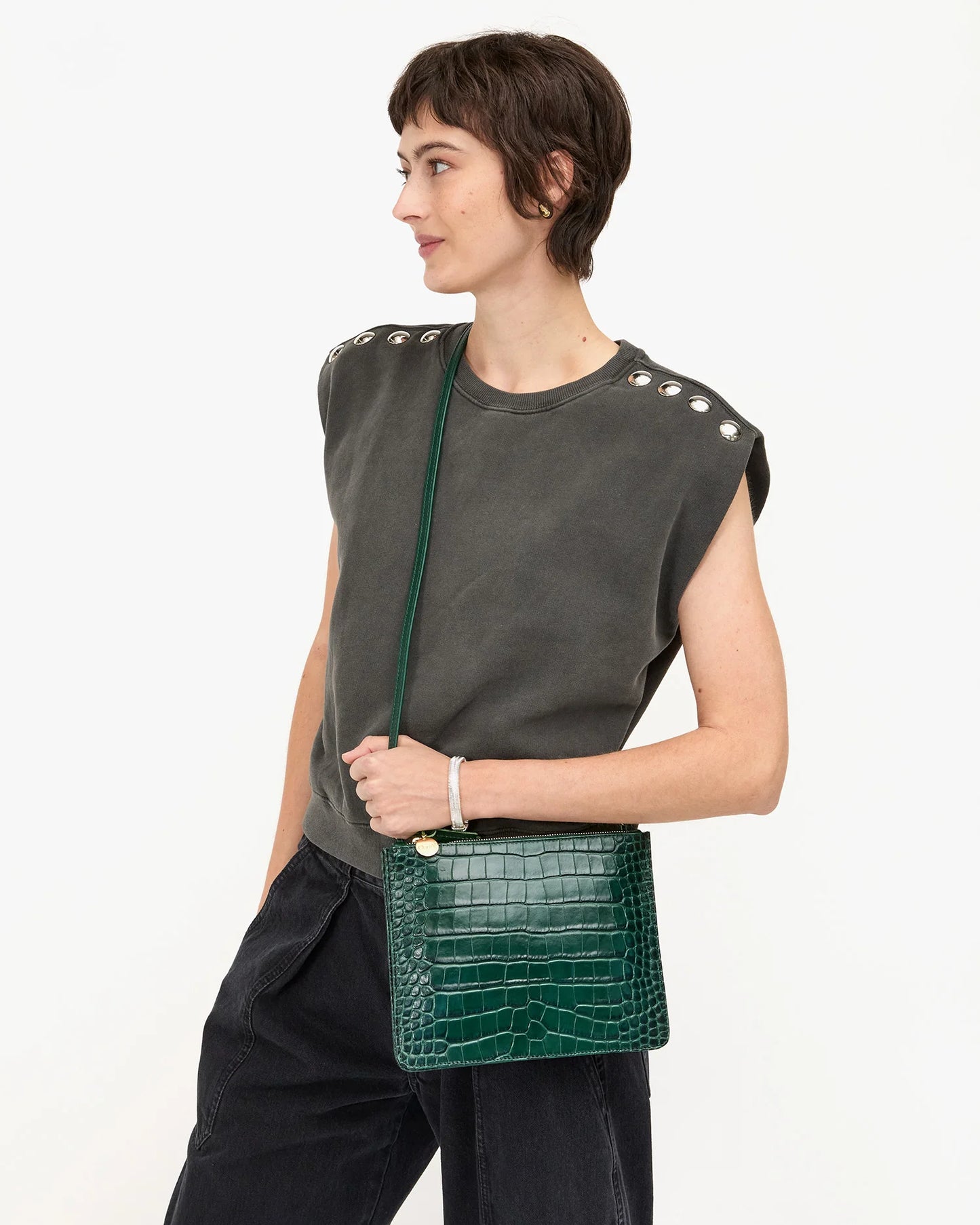 Woman holding a green crocodile-patterned handbag from Clare V.
