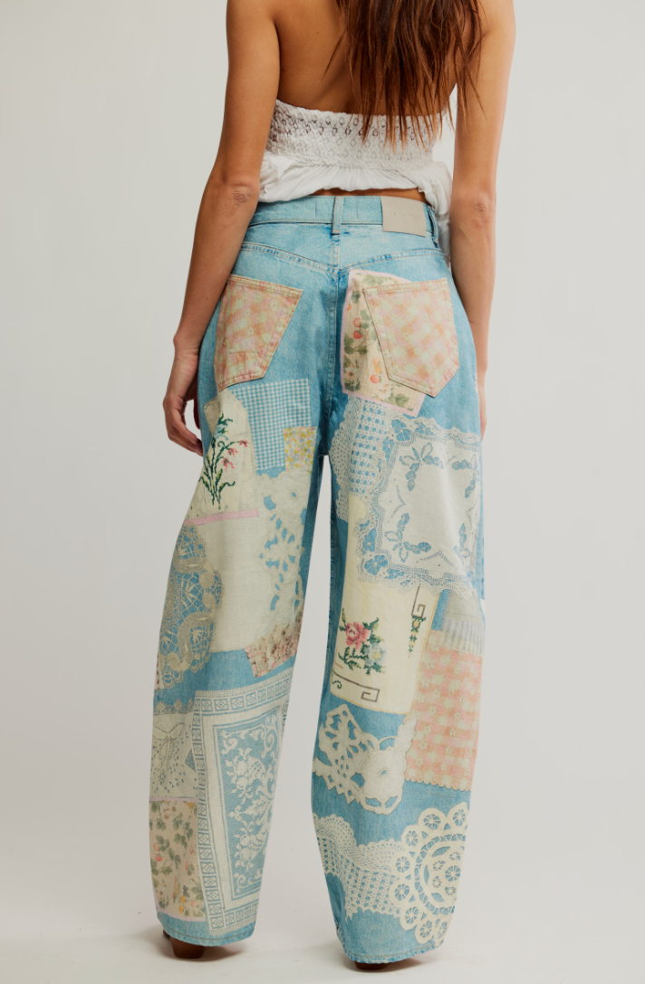 Person wearing patchwork pants with floral and geometric patterns on a plain background