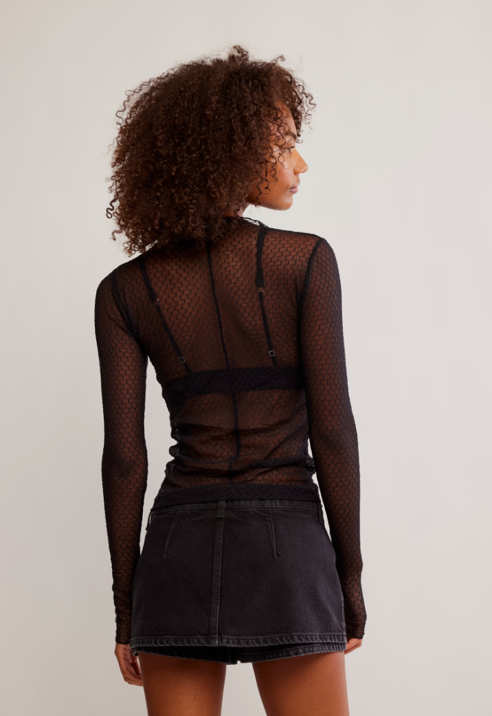 Person wearing a sheer black long-sleeve top and black denim skirt by Free People