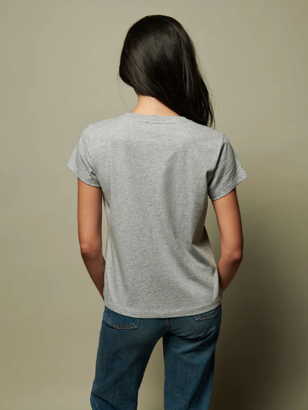 Person wearing a gray t-shirt and blue jeans against a beige background