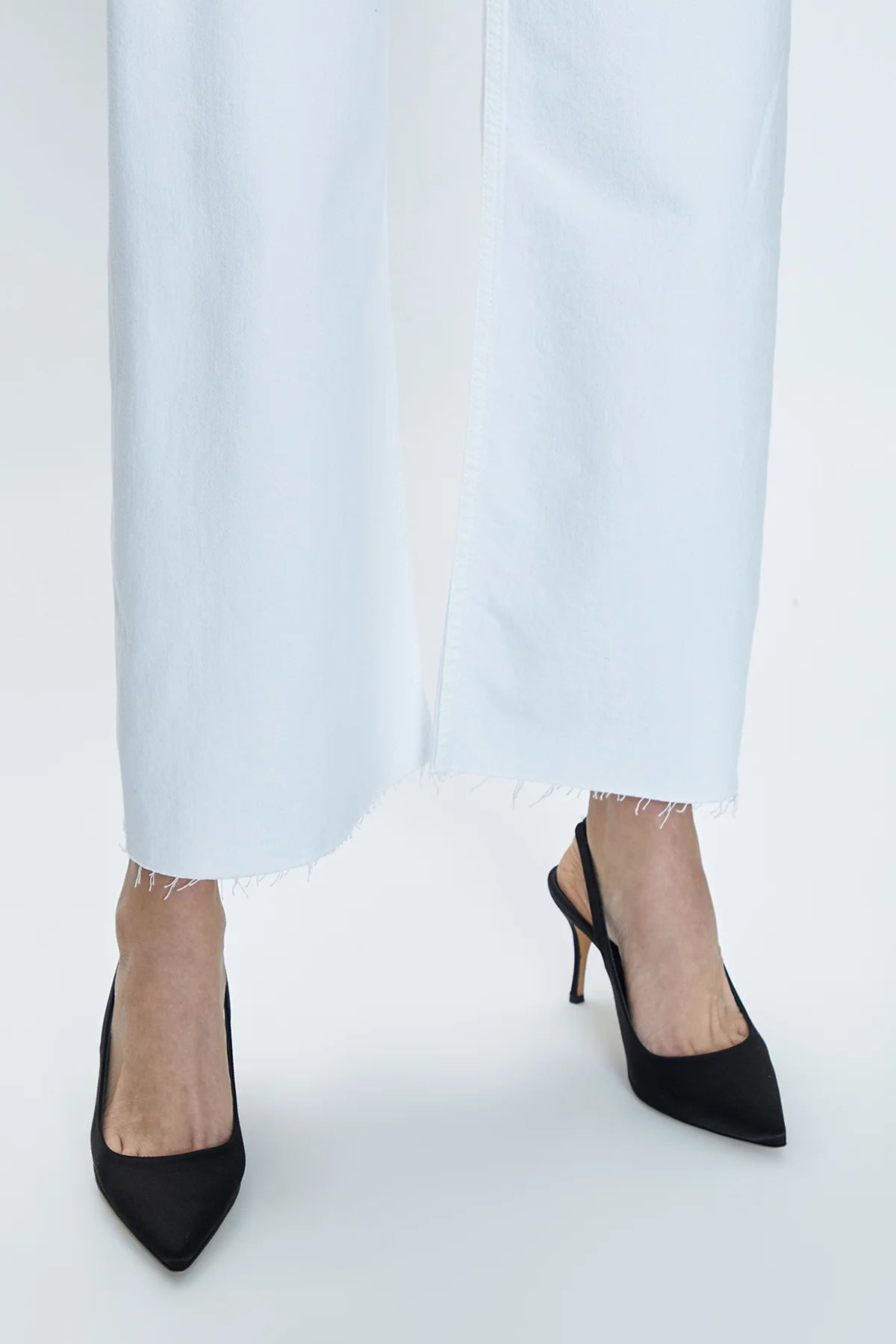 Close up view of the bottom hem on a pair of white denim HIgh rise wide leg jeans