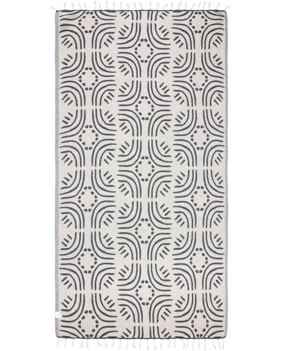Unfolded view of the reverse side of the beach towel featuring a white background with navy line and dot design throughout and tassels at the ends