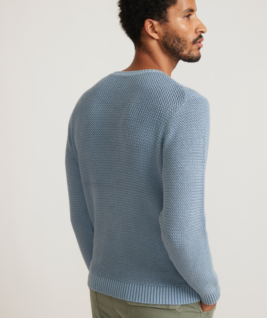 Back view of man wearing a blue garment dye crew sweater from Marine Layer