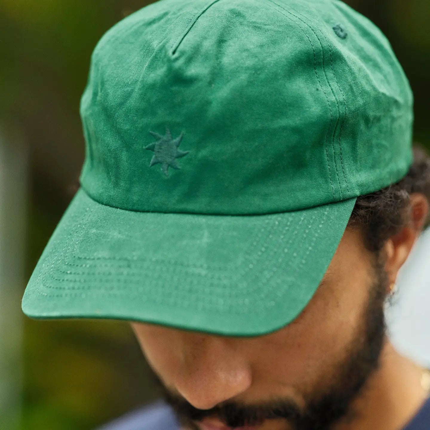 A man wearing the Mollusk Waxed Sunsplash Hat in the color Forest