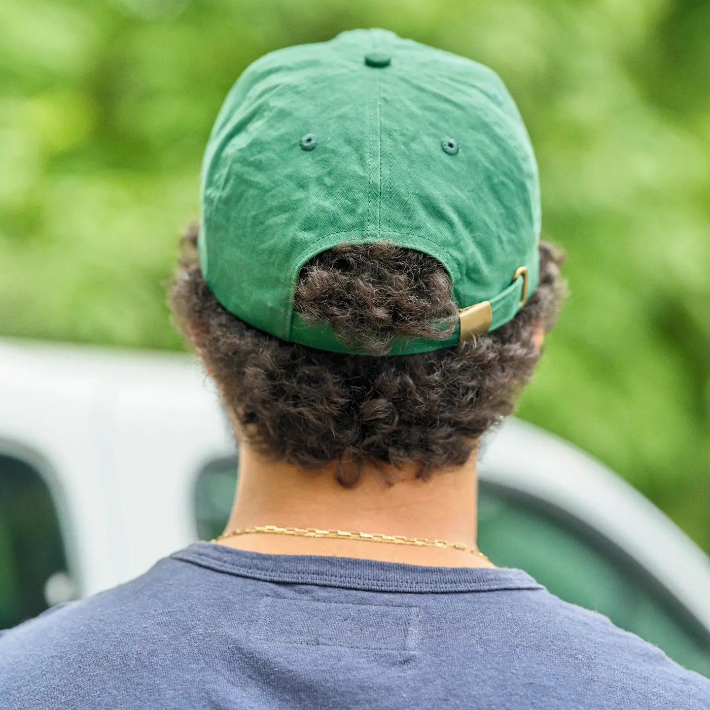 Man wearing a green hat with adjustable back closure