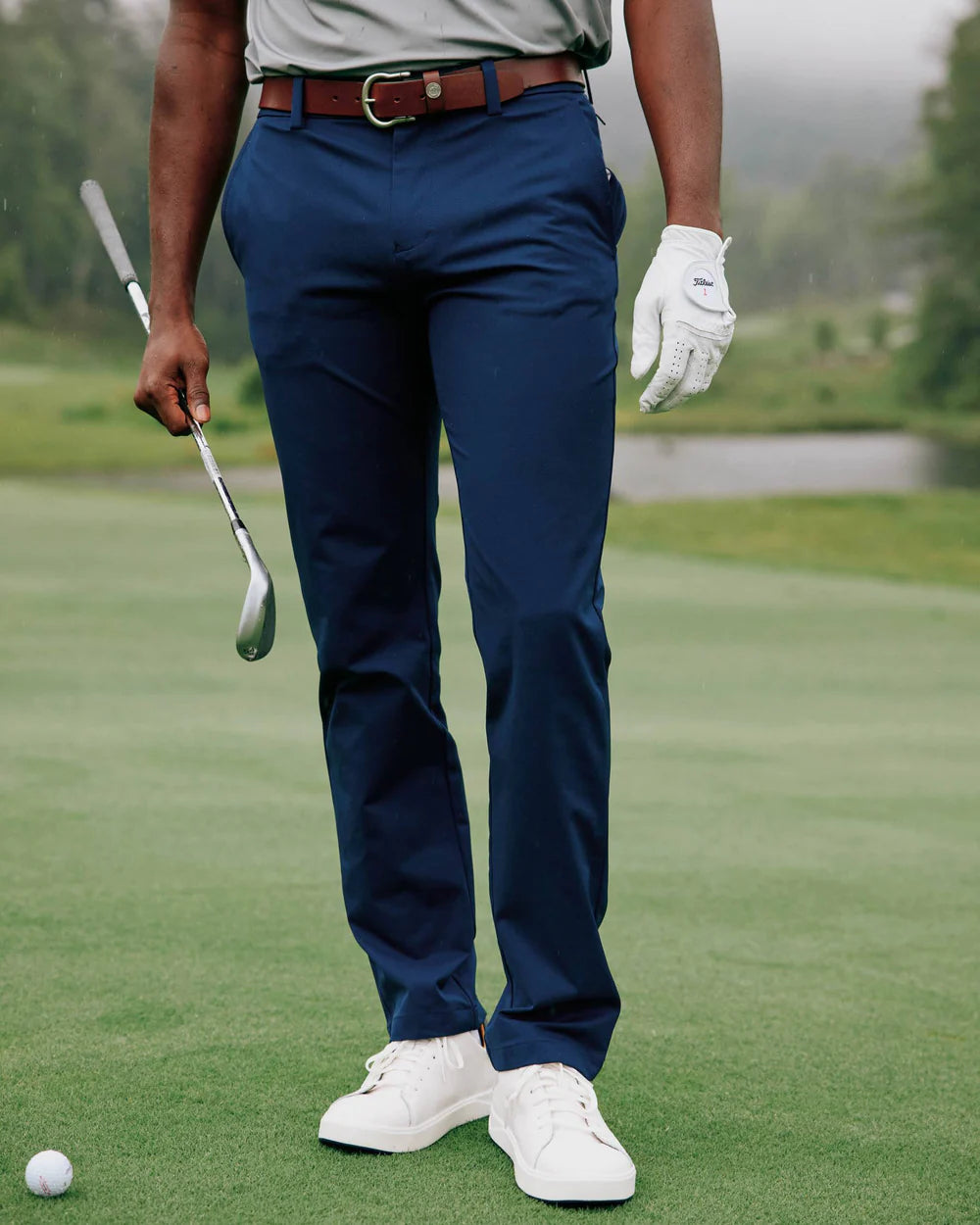 Man playing golf in the blue performance pants by Southern Tide