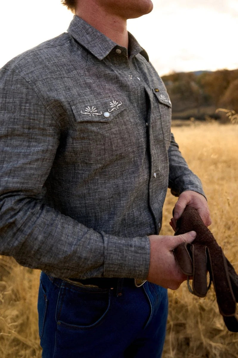 This washed black men's pearl snap shirt features embroidery detail on the chest flap pockets