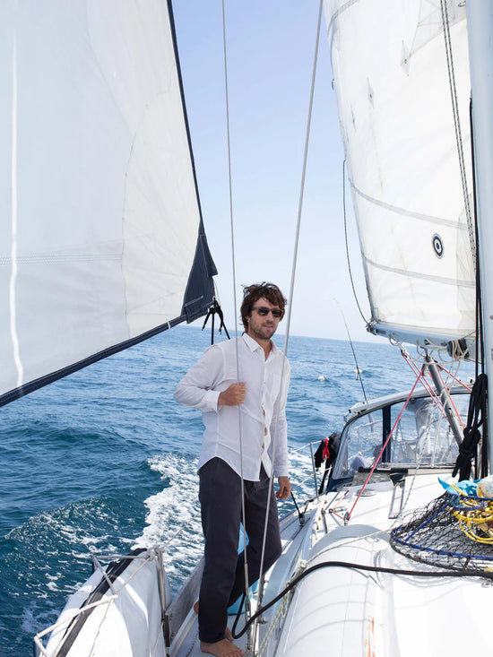 Man on a sailboat wearing Mollusk's faded navy Scout Pants
