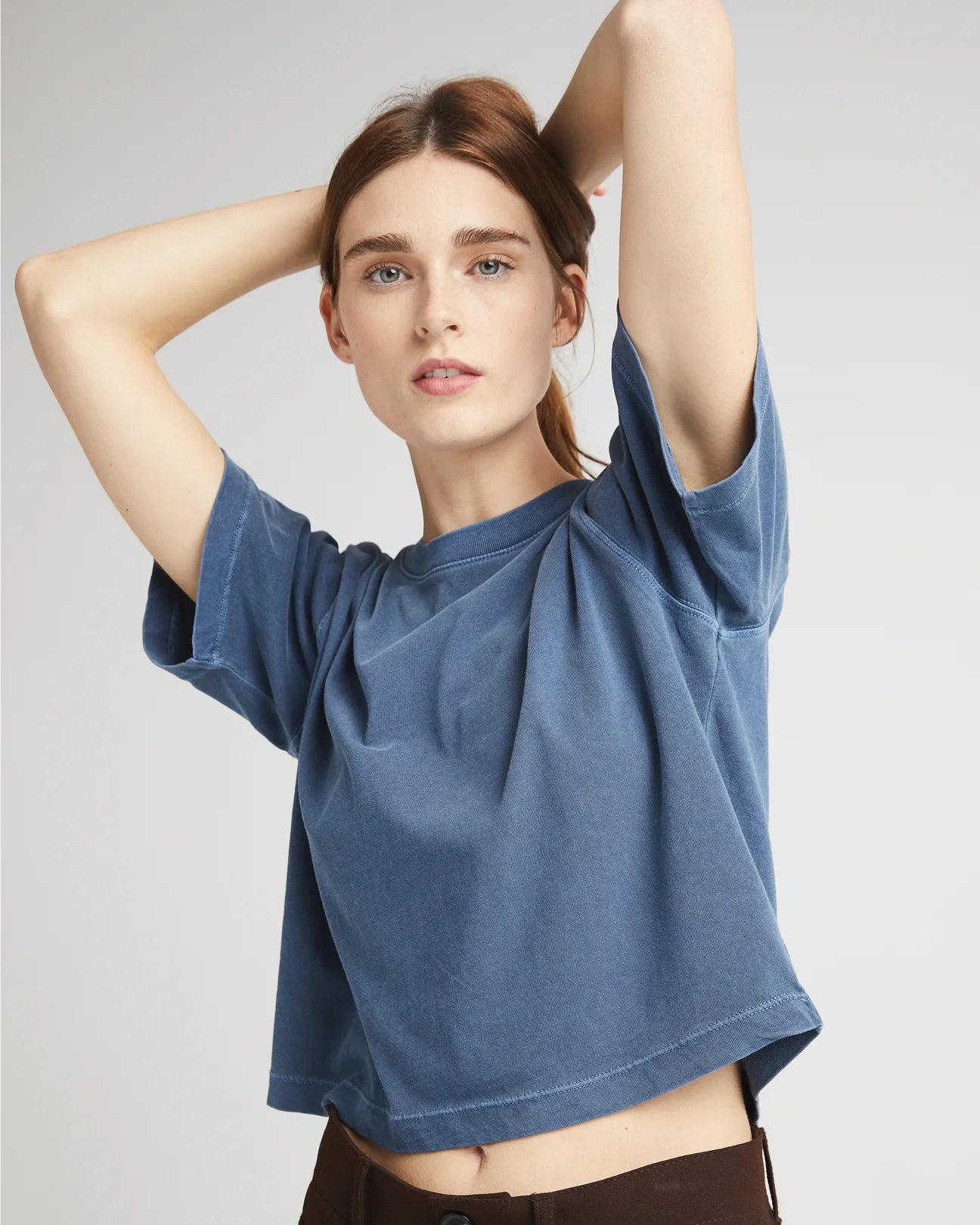 front view of a woman wearing a relaxed fit short sleeve cropped t-shirt in a mid-blue color called moonlit ocean