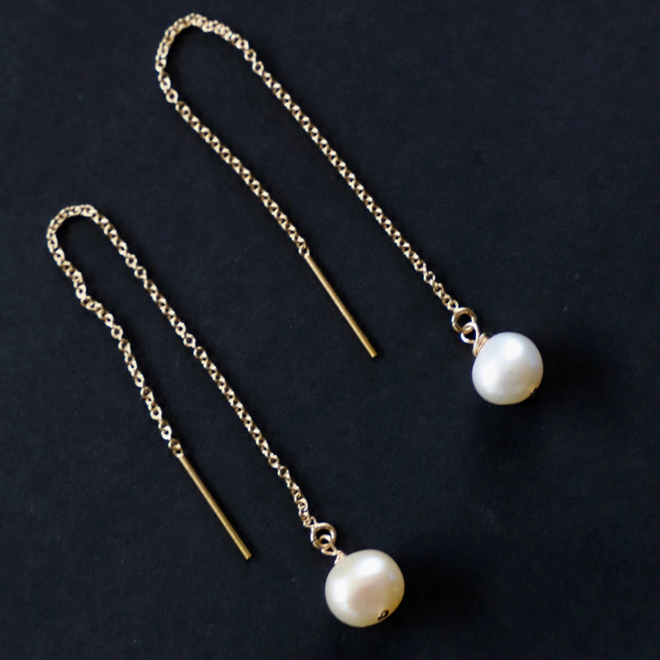 Pearl drop earrings on a dark background