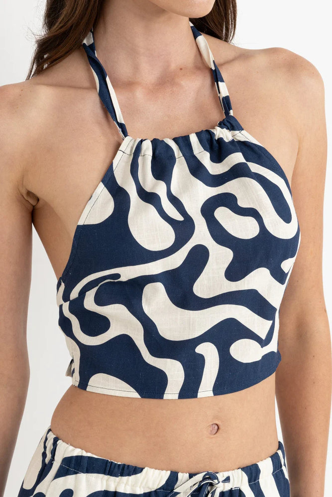 Woman wearing a blue and white patterned halter top and shorts on a plain background