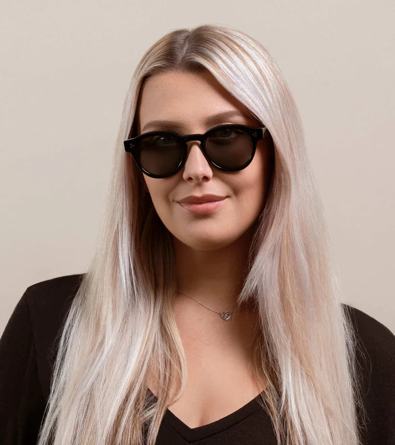 A woman wearing the Zelti Unisex Round Polarized Sunglasses by RAEN